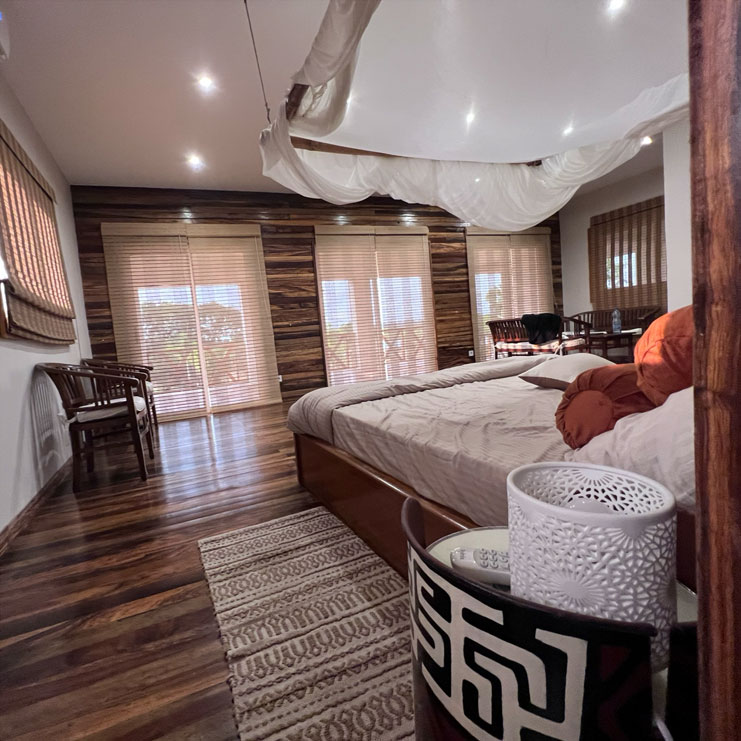 Chambre de Ndossi Village avec lit sous moustiquaire, bois et ventilateur